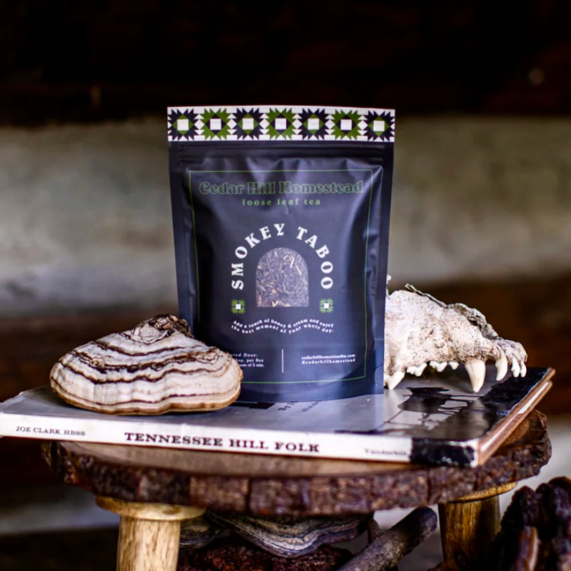 Package of 'Smoky Taboo' tea on a wooden stand with natural elements