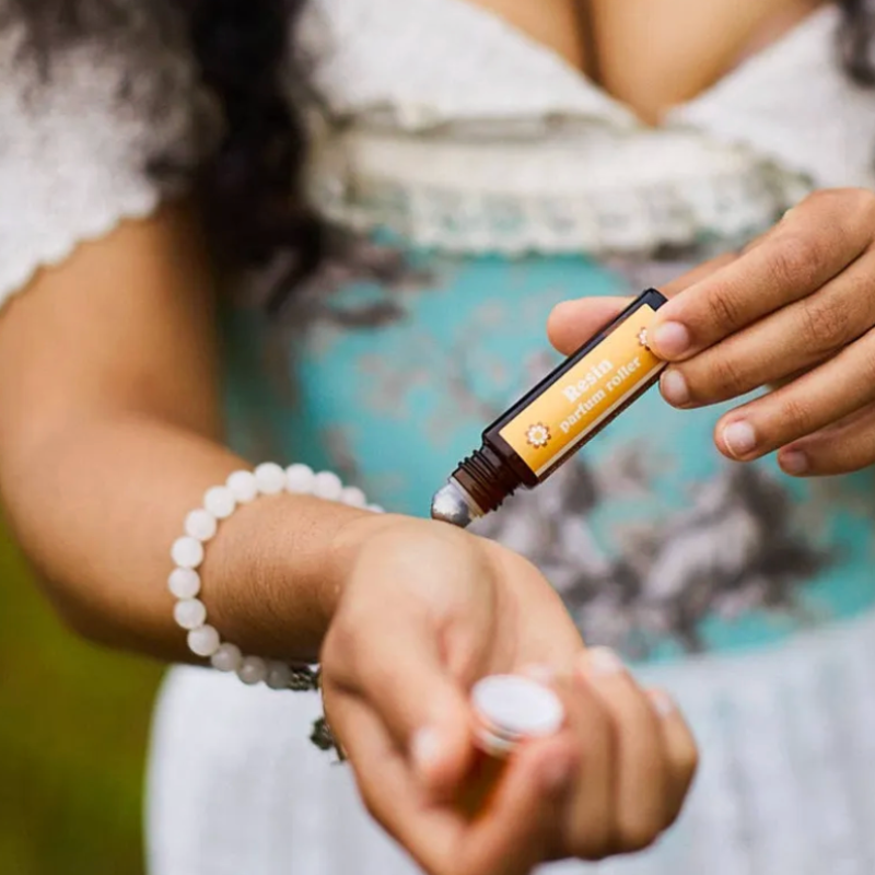 Person applying a rollerball of natural perfume product to their wrist.